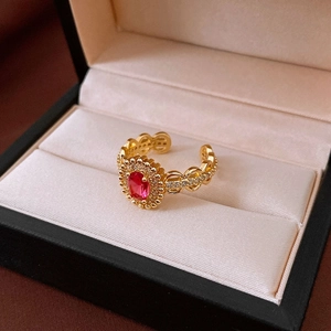 Detail of gold plated ring with red oval gemstone and hollow chain band design