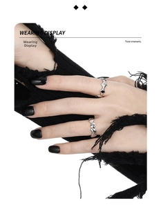 Detail of star-shaped thorn and heart chain silver rings on black knit sleeve