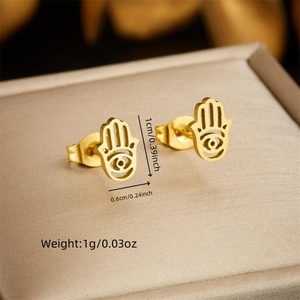 Golden Hamsa Hand earrings in stainless steel on a beige jewelry cushion