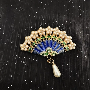 Macro view of Chinese fan brooch with blue enamel, white pearls and gold metal finish
