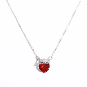 Macro shot of silver heart necklace with red zircon pendant and wing-like accents