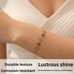 Detail of gold-plated clover bracelet with black and white motifs on model wrist
