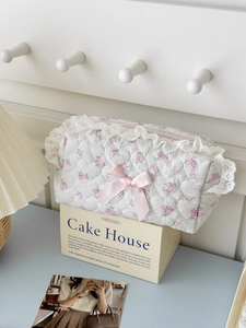 Close-up of heart-quilted floral makeup bag with lace trim and pink ribbon bow detail