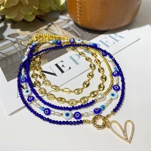 Detail view of multi-layered gold coffee bean chain with evil eye beads and pearls