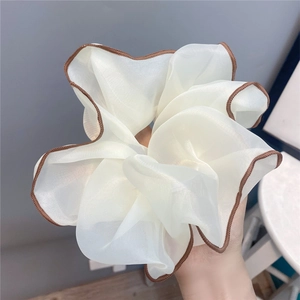 Macro detail of large white chiffon scrunchie with elegant brown contrast piping edge