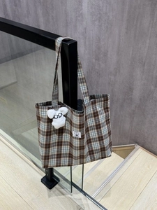 Detail of brown and blue plaid canvas tote with a cute white cartoon puppy keychain
