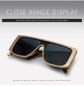 Close-up of retro oversized one-piece sunglasses with bronze metal frame and dark lenses