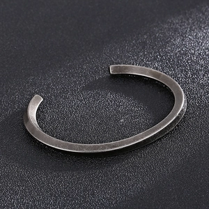 Vue macro d'un bracelet jonc torsadé en forme de C sur fond de cuir noir texturé