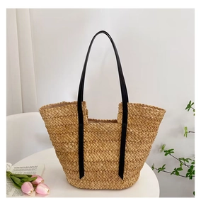Détail du sac cabas en paille tissé avec anses en cuir noir et doublure rose clair
