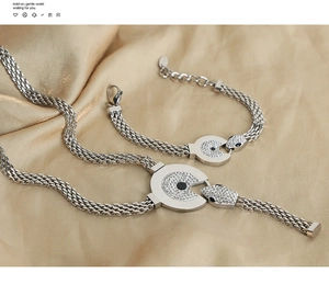 Macro shot of silver snake-shaped jewelry set with crystal paving on champagne silk