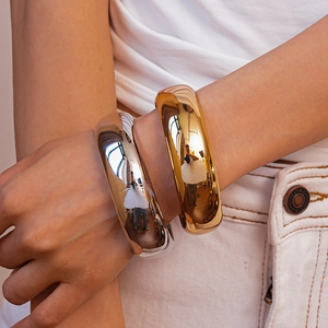 Close-up of polished silver and gold chunky metal bracelets on a person's wrist