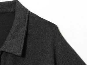 Makroaufnahme von kohlengrauem Wollstoff und präzisen Nähten am Kragen der Jacke
