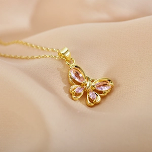 Macro shot of gold butterfly pendant with pink crystals on soft fabric background