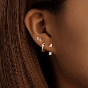 Close-up of a woman wearing a 3-piece set of gold marquise zircon stud and hoop earrings