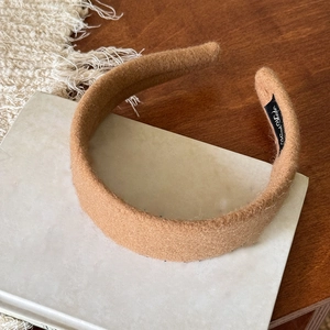 Dettaglio del cerchietto in velluto marrone con etichetta Hand Made su tavolo retrò
