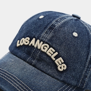 Detailed macro view of the 3D embroidered Los Angeles lettering on blue denim fabric