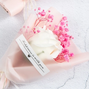 Close-up of artificial white rose and pink baby's breath mini bouquet in gift wrap
