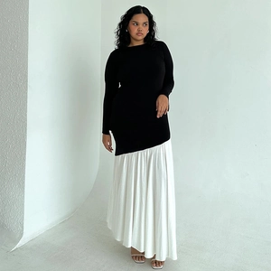 Detail of elegant two-tone long-sleeve dress with black bodice and white pleated skirt
