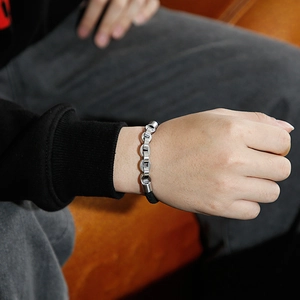 Close-up of men's bracelet with silver stainless steel chain and black braided leather strap