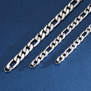 Three widths of stainless steel Figaro chains in silver finish on blue fabric background