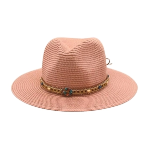 Détail d'un chapeau de paille rose poudré avec chaînes dorées, perles et cordon