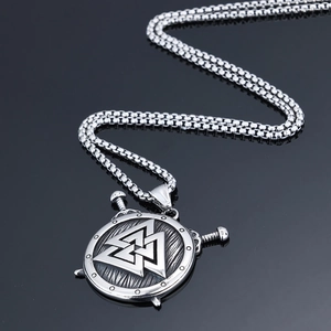Macro shot of a Viking shield pendant with Valknut symbol and twin swords on black mirror