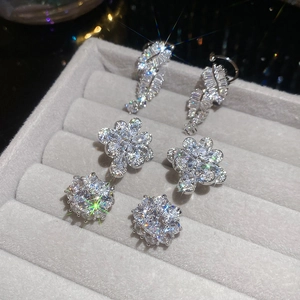 Macro shot of three pairs of silver zircon earrings with leaf and floral motifs