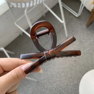 Detail of tortoiseshell bow hair claw clip showing resin texture and metal spring