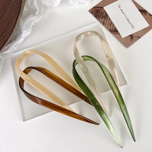U-shaped hair pins in pink, green, and brown resin displayed on a decorative glass tray