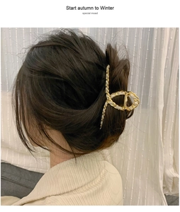 Detail of elegant gold chain hair claw with white ribbon weaving on model hair