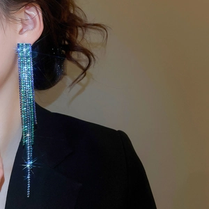 Close-up of long blue-green gradient rhinestone fringe earrings worn by a model
