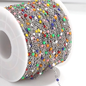 Macro detail of multicolored enamel beads on a stainless steel chain for DIY jewelry making