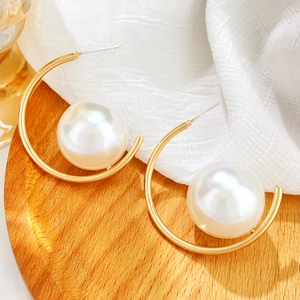 Macro view of C-shaped gold earrings with large pearls and S925 silver stud engraving