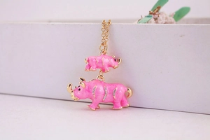 Close-up of pink enamel rhino necklace with sparkling crystals and gold metal finish