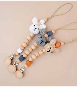 Detail of baby pacifier clips featuring wooden beads and crochet bunny designs