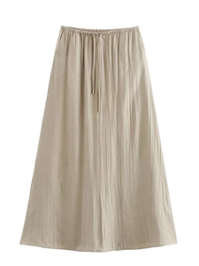 Détail d'une jupe plissée beige clair avec taille élastique à cordon et texture verticale
