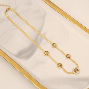 Gold tree of life necklace set with zirconia stones on a marble display tray