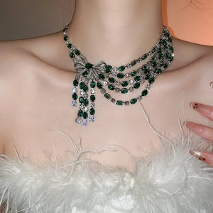Detail of emerald gemstone tassel necklace with a crystal bow worn on neck