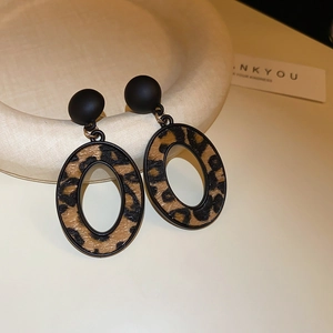 Détail de boucles d'oreilles ovales à motif léopard avec clous noirs sur plateau