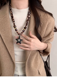 Detail of leopard print fabric necklace with star pendant worn with a beige blazer