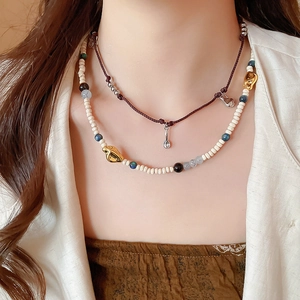 Detail of layered brown cord necklace and beaded chain with golden accents