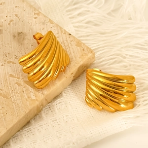 Boucles d'oreilles éventail dorées polies sur socle en pierre et fond en tissu