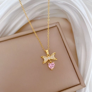 Detail of gold bow necklace with micro-pave diamonds and a pink heart zircon pendant