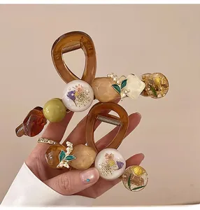Détail de pinces à cheveux avec muguet en résine et incrustations de fleurs séchées