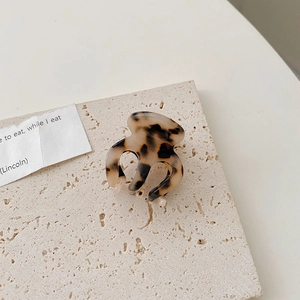 Détail d'une pince à cheveux en acétate motif léopard écaille sur fond de pierre grise