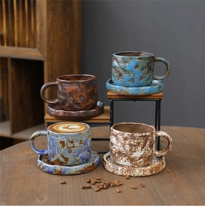 Detail view of four sets of vintage handmade ceramic coffee cups and saucers on a wooden table