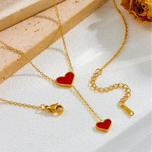 Elegant gold stainless steel necklace with two vibrant red heart pendants on stone surface