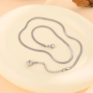 Sleek silver stainless steel herringbone chain necklace with a heart pendant on a tray