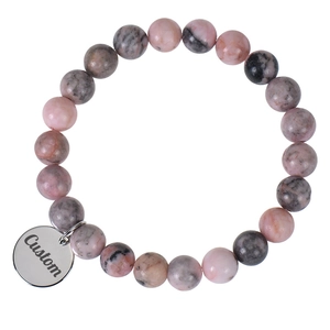 Detail of natural pink stone beaded bracelet with custom engraved round metal pendant