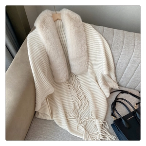 Close-up of knit poncho featuring premium faux fur collar and elegant fringe details